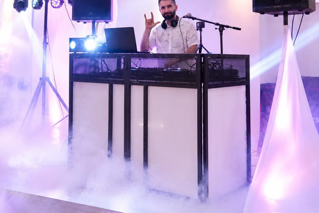 Beleuchtetes DJ-Pult im Bodennebel, warmes Licht im Saal