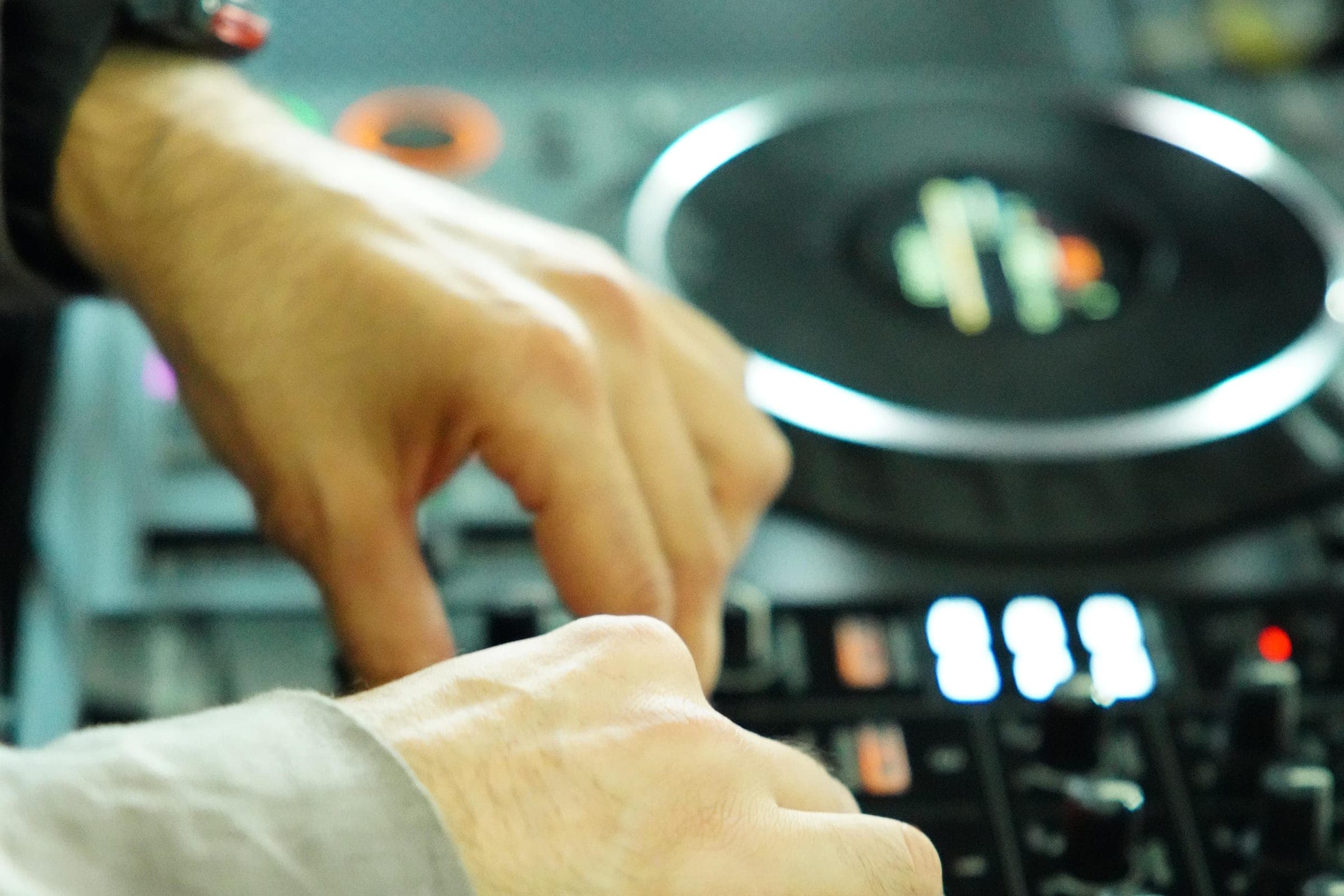 Hände am DJ-Controller, Nahaufnahme der beleuchteten Bedienelemente