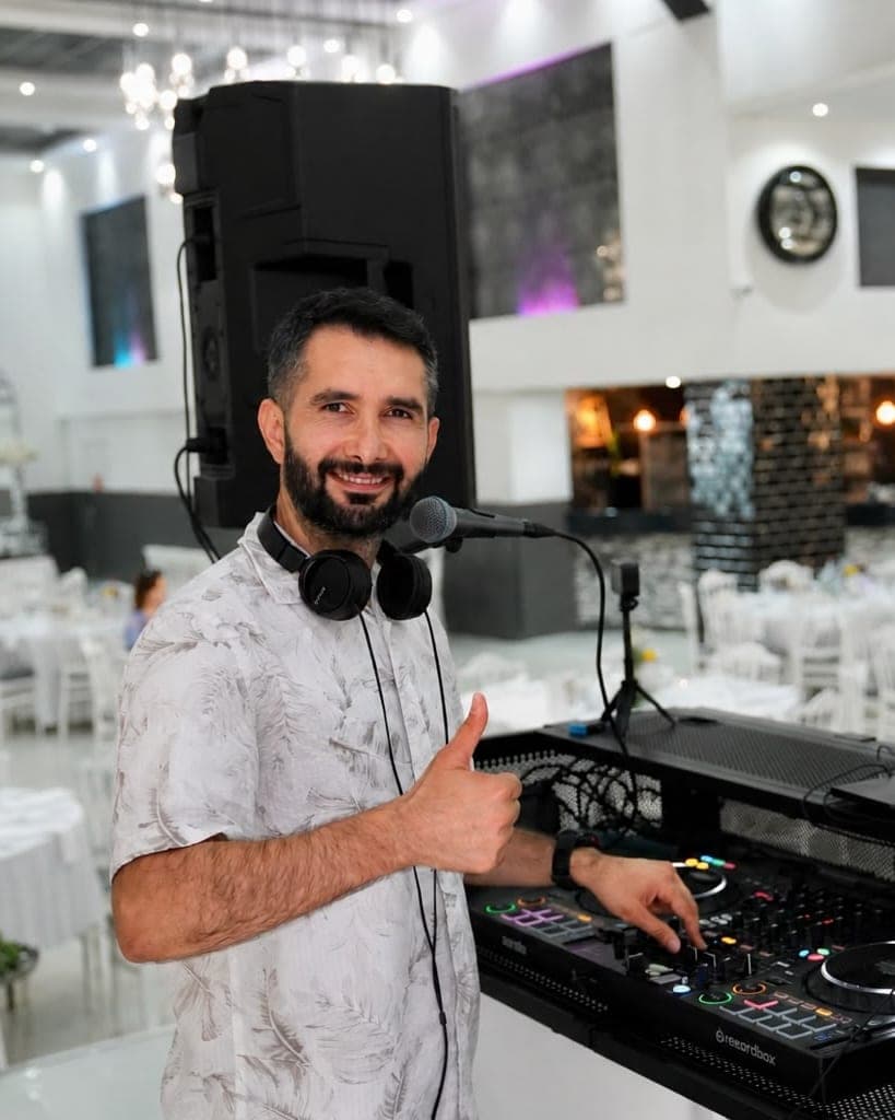 Veysel Durmuş am DJ-Pult, lächelnd mit erhobenem Daumen in die Kamera