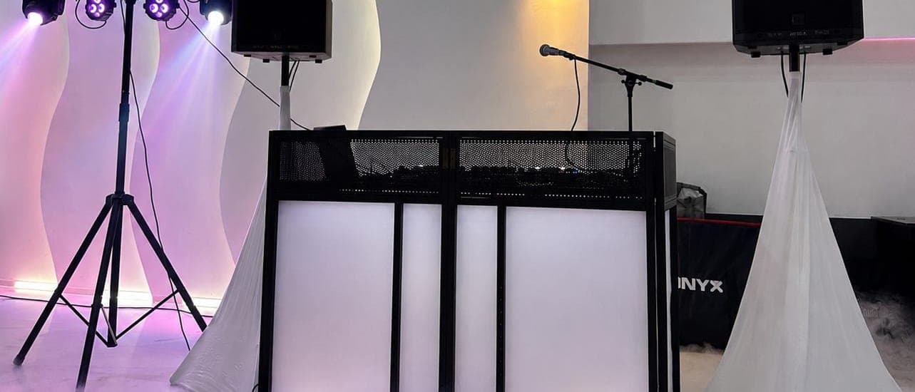Beleuchtetes DJ-Pult im Bodennebel, farbige Lichteffekte an der Wand dahinter