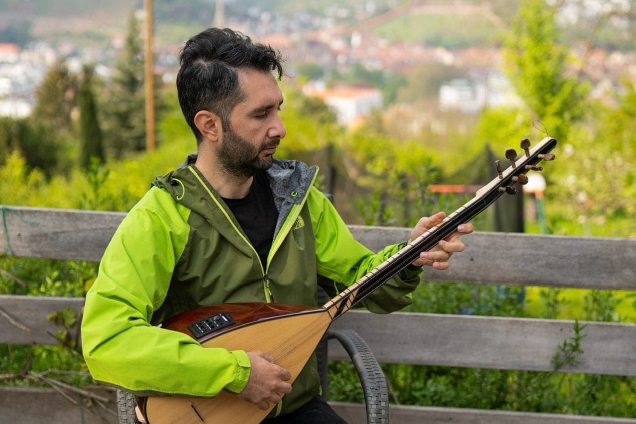 Veysel Durmuş spielt Bağlama im Freien, Weinberge im Hintergrund
