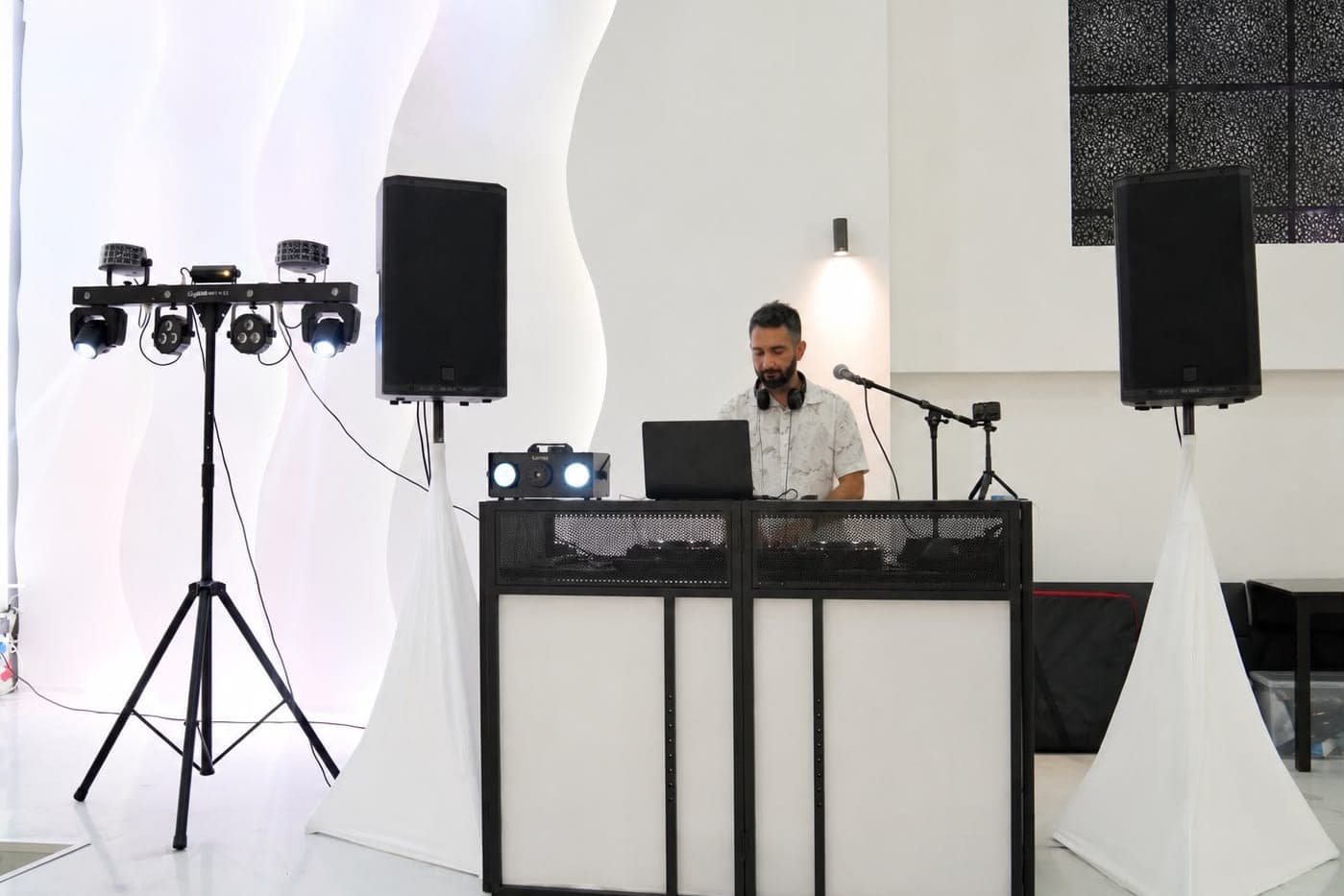 Aufgebaute Technik vor der Veranstaltung: DJ-Pult, Lautsprecher und Lichtstative im Saal